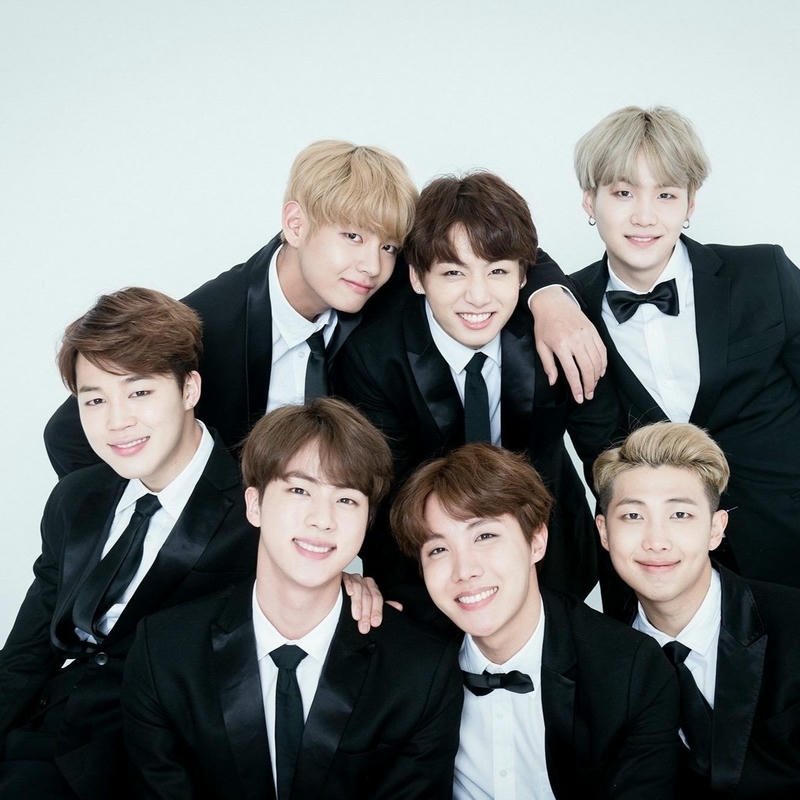 BTS members sitting together white shirts casual group photo