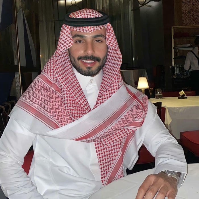 Handsome man sitting at table wearing red traditional headscarf