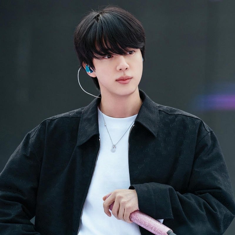 Jin standing stage black jacket holding microphone handsome view