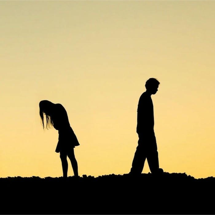 Lonely person silhouette walking away from another at sunset