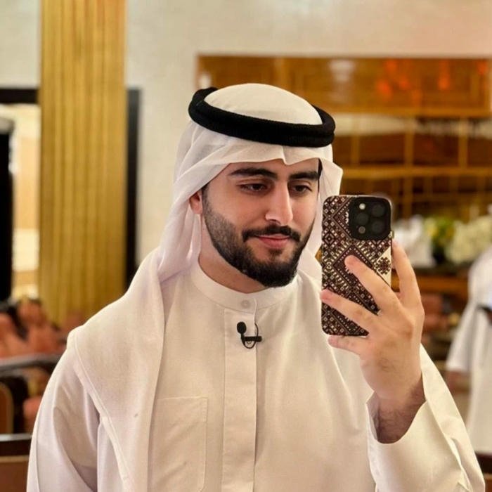 Man taking mirror selfie wearing white traditional arab clothes