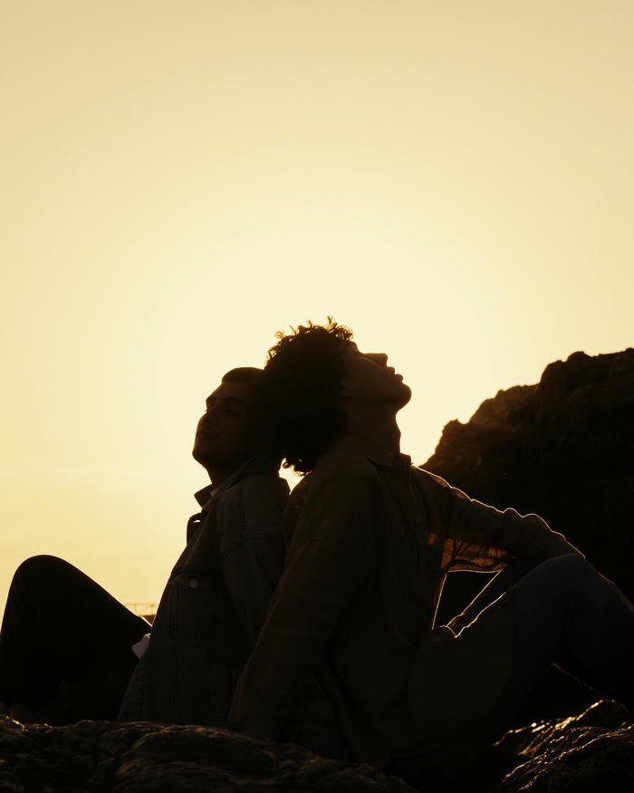 Sad love images silhouette of couple sitting back to back at sunset