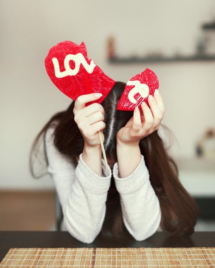 Sad love quotes girl hiding face with book saying love
