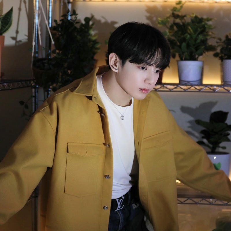 V wearing yellow cardigan sitting indoor warm lighting view