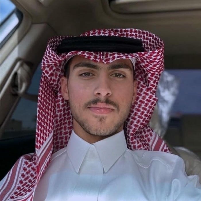 Young man taking selfie in car wearing red shemagh