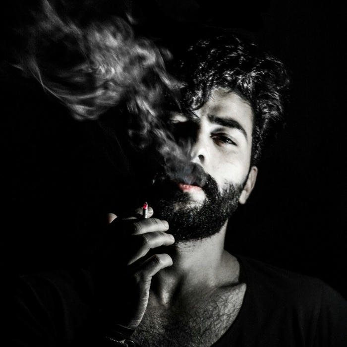 Bearded man smoking cigarette with thick smoke cloud black white