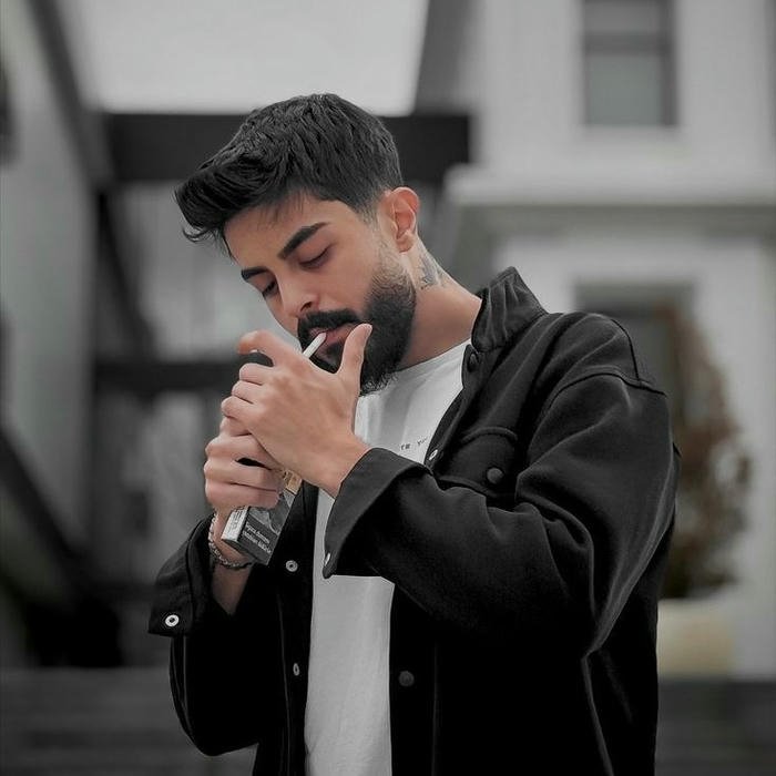 Cool fashion boy lighting cigarette looking down style