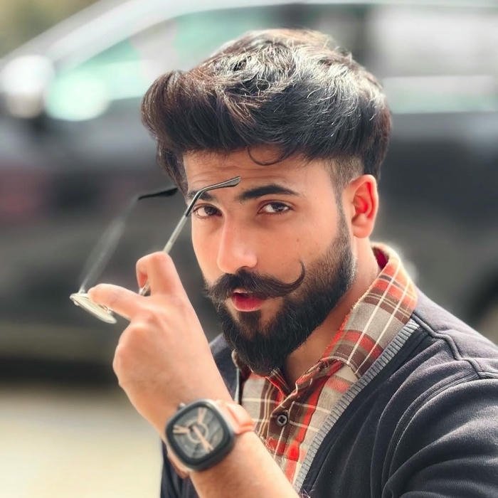 Cool guy with beard adjusting sunglasses looking at camera