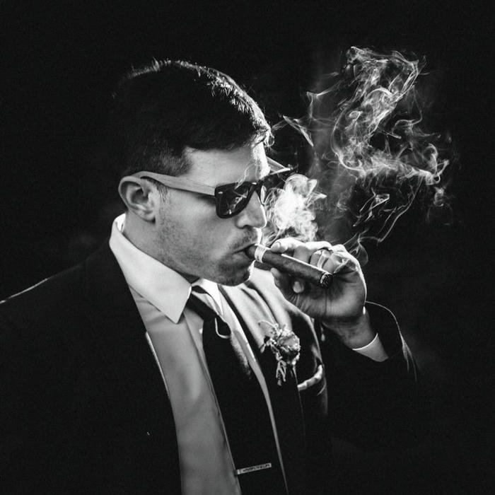 Cool man in suit and sunglasses smoking cigar monochrome