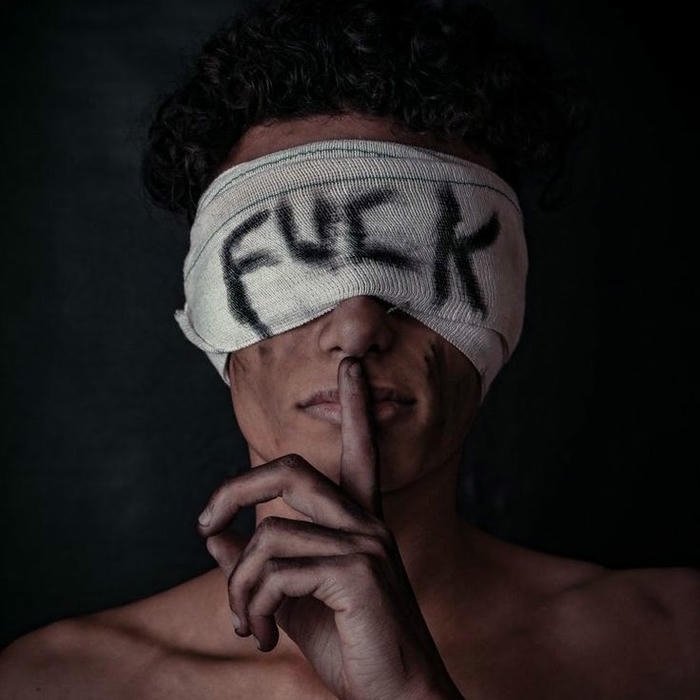 Edgy boy tape over eyes making silence sign