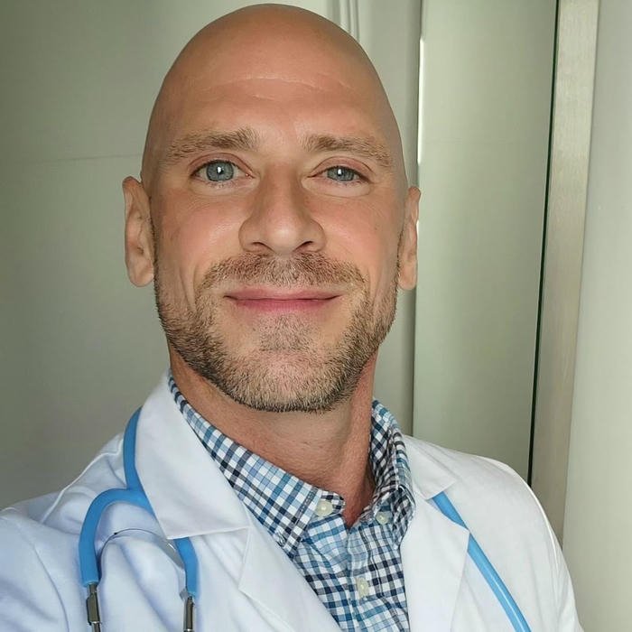 Famous bald doctor smiling wearing blue scrubs avatar image