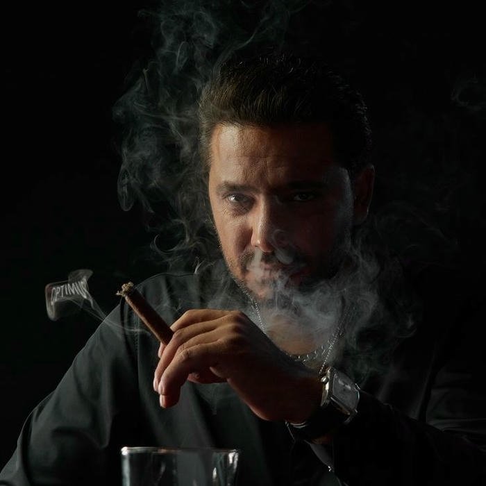 Handsome man in suit lighting cigar with lighter close up