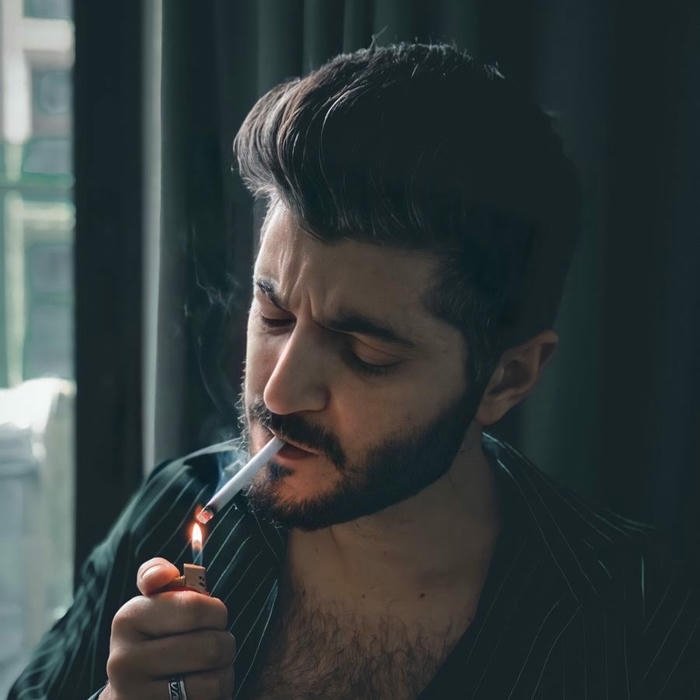 Handsome man looking down lighting cigarette dark atmosphere