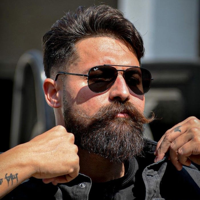 Intense look man with thick beard and sunglasses outdoors
