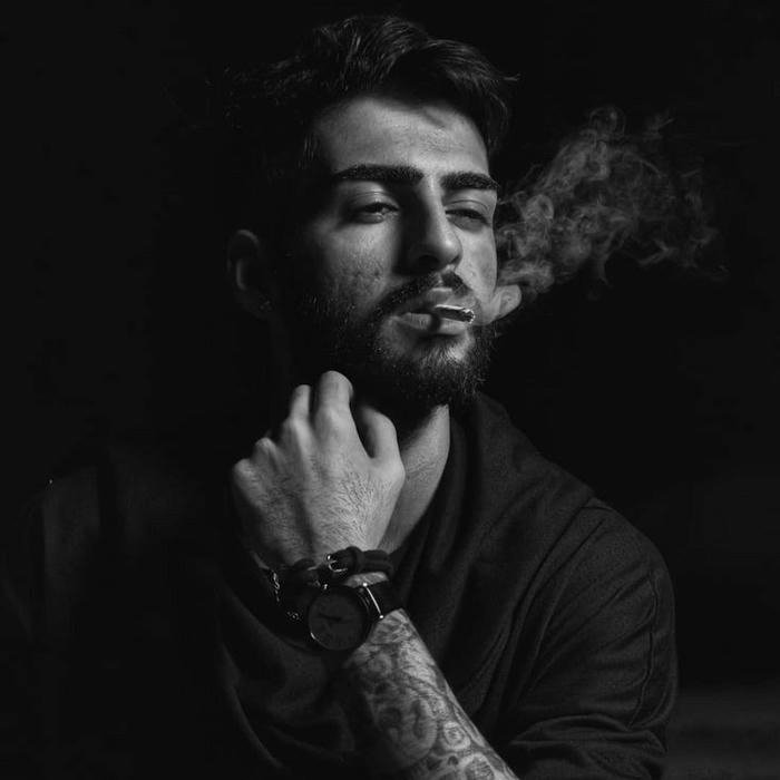 Moody black and white man exhaling smoke dark background