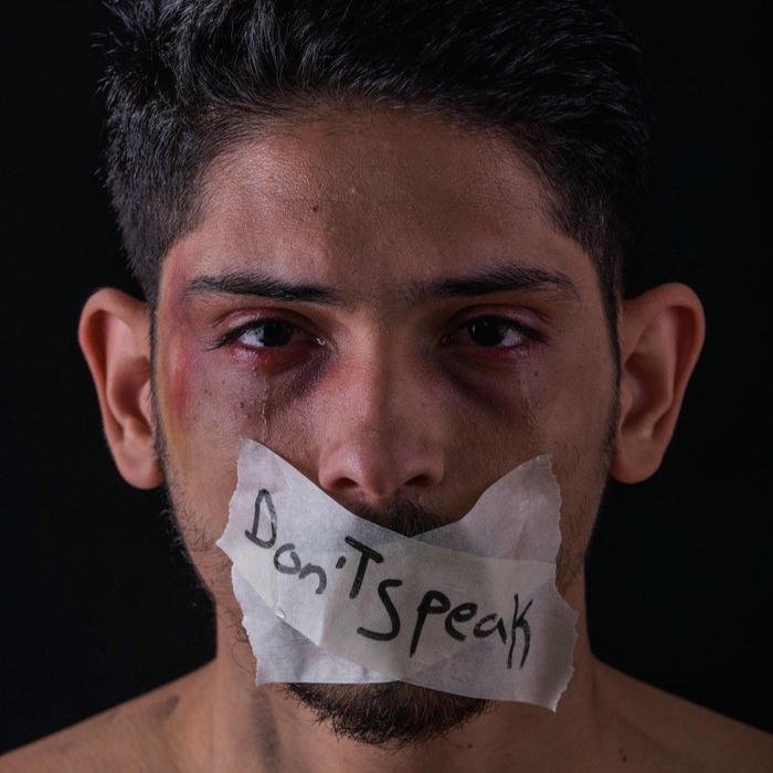 Scared boy with taped mouth looking at camera