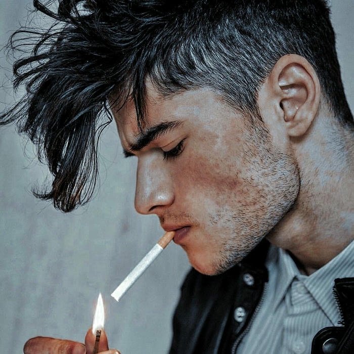 Side profile young man lighting cigarette wearing white shirt